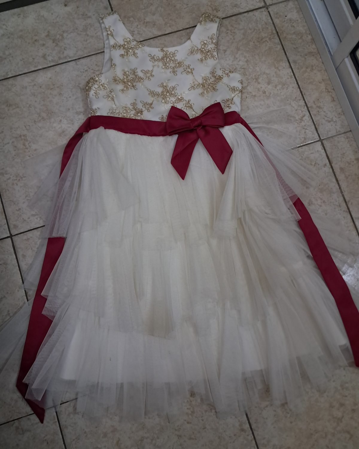Vestido de niña en blanco con detalles dorados y lazo fucsia